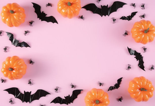 Photo happy halloween holiday background with trick or treat, pumpkins, candy and spiders on pastel pink background.