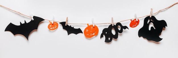 happy halloween holiday concept. bats, pumpkins and ghosts on rope on white isolated background