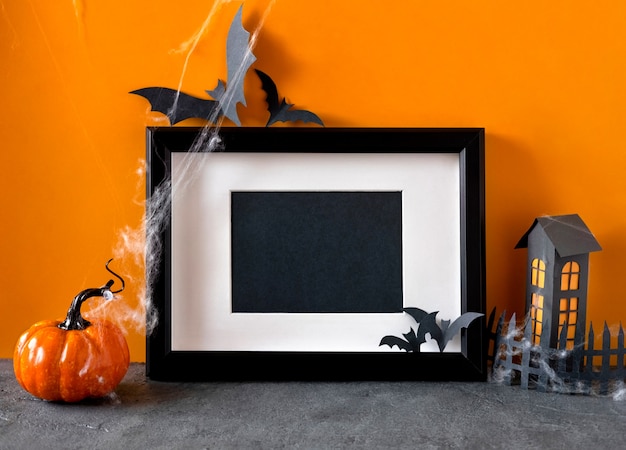 Photo happy halloween holiday concept. black frame on orange background. halloween decorations, pumpkins, bats, black frame.