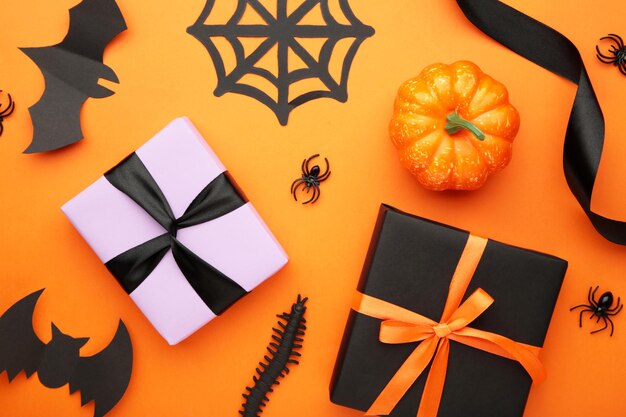 Happy Halloween holiday concept Flat lay gift boxes orange pumpkins bats spiders on orange background Halloween greeting card template Top view