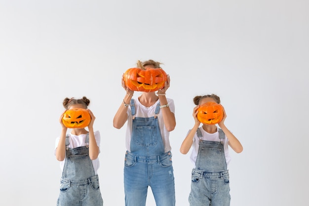 Happy halloween and holidays concept - A mother and her daughters with pumpkins. Happy family preparing for Halloween.