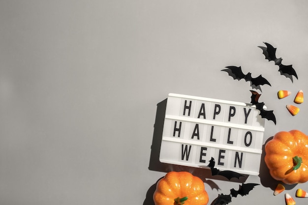 Happy halloween lightbox sign board with pumpkin bats and candy on a grey background