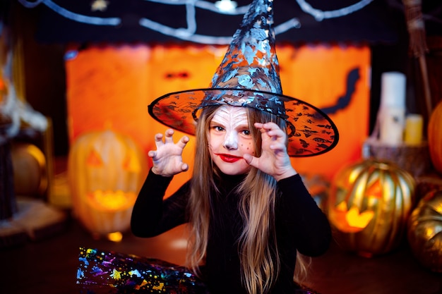 Счастливого Хэллоуина. Маленькая красивая девушка в костюме ведьмы празднует с тыквами