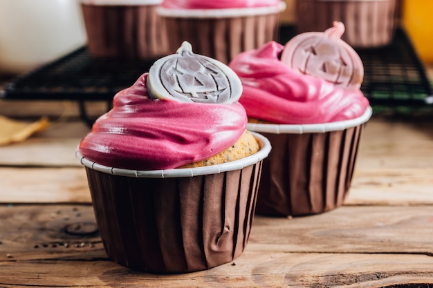 Happy Halloween pumpkin cupcakes decorated with pink cream