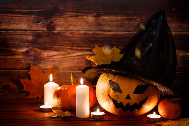 Happy Halloween! Pumpkin in a witch hat on a wooden background. Place for text.