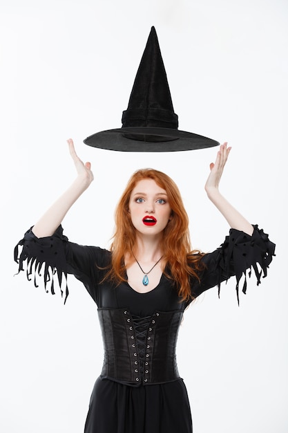 Happy Halloween Sexy ginger hair Witch with magic hat flying over her head. Isolated on white background.