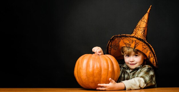 Foto buon halloween sorridente bambino ragazzo in cappello da strega con halloween zucca piccolo bambino mago con