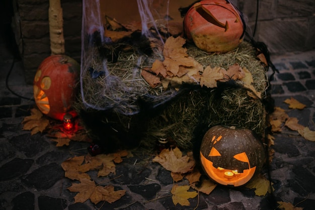 Happy Halloween Spooky Jacko'lantern with glowing faces and cobweb in dark Pumpkin with scary carved face on hay with candle light modern festive halloween street decor