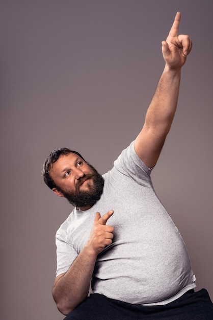 Happy handsome bearded excited man in gray t-shirt with hands up celebrating.