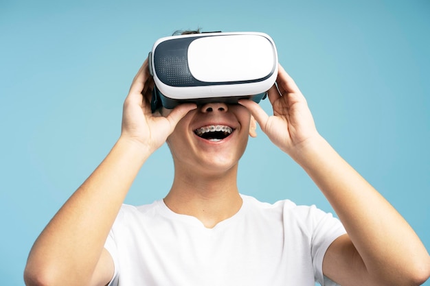 Happy handsome boy wearing VR glasses and playing video game isolated on blue background