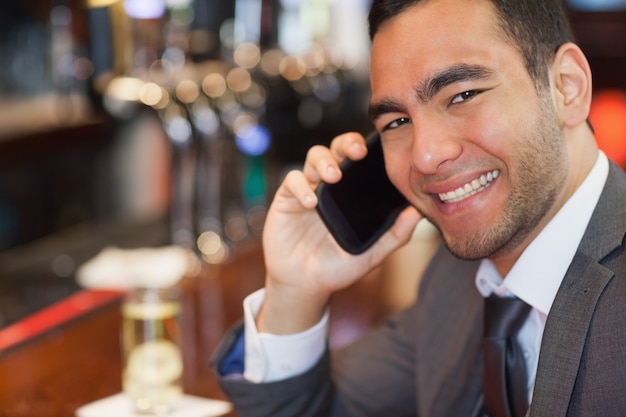 Happy handsome businessman on the phone having a drink