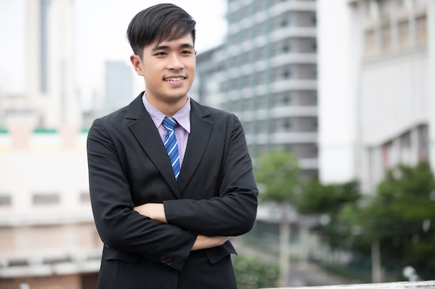 Happy handsome businessman standing and smiling at outdoor