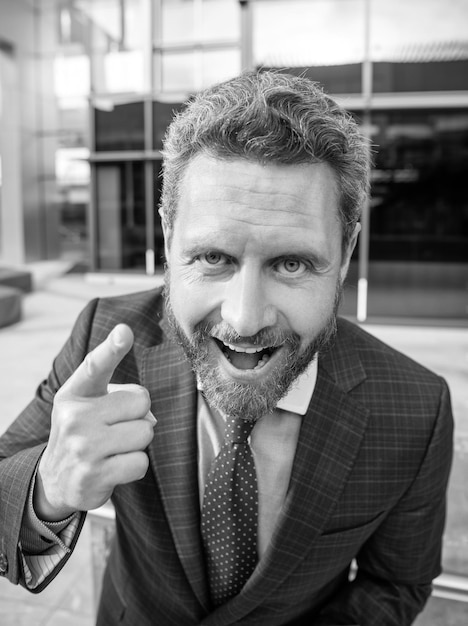 Happy handsome entrepreneur in businesslike suit outside the office point finger emotions