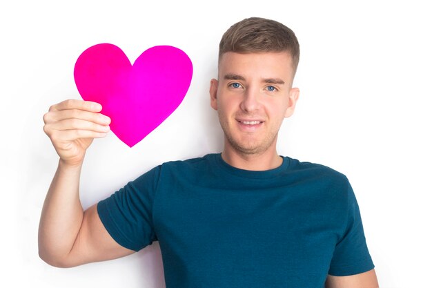 Happy handsome guy nice boy holds valentine in hand, smiling. Young beautiful man got card for Saint Valentine's Day,  postcard in shape of red heart, smiling. Copy space, 