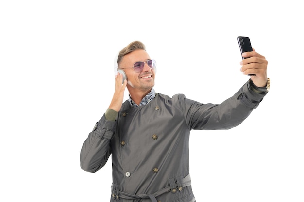 Happy handsome man use smartphone listening to music in headphones isolated on white, vodeo call.