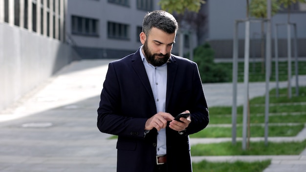 Happy  handsome man using mobile phone apps, texting message, browsing internet, looking at smartphone.