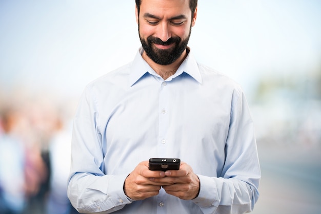 Felice uomo bello con la barba parlando al cellulare su sfondo unfocused