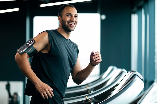 Happy Handsome Young Black Male Athlete Jogging On Treadmill At Gym