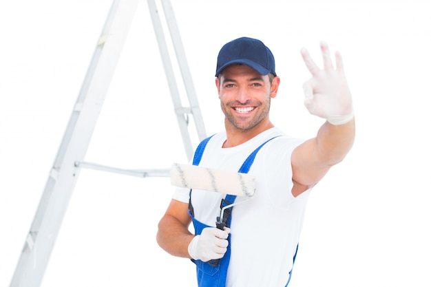 Happy handyman with paint roller gesturing okay