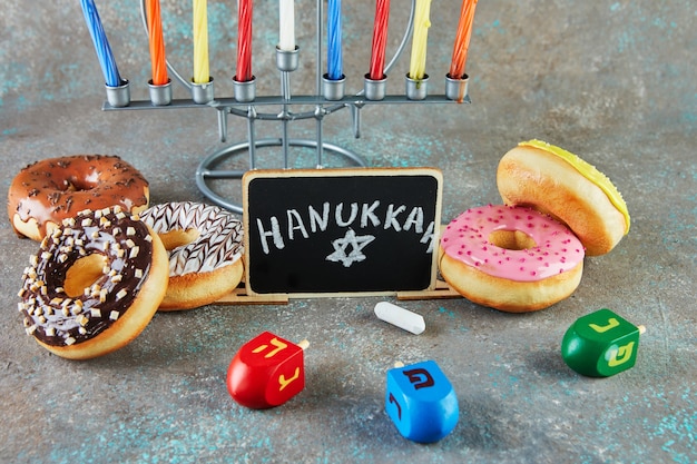 Happy Hanukkah and Hanukkah Sameach - traditional Jewish candlestick with candles, donuts and spinning tops with the inscription Hanukkah