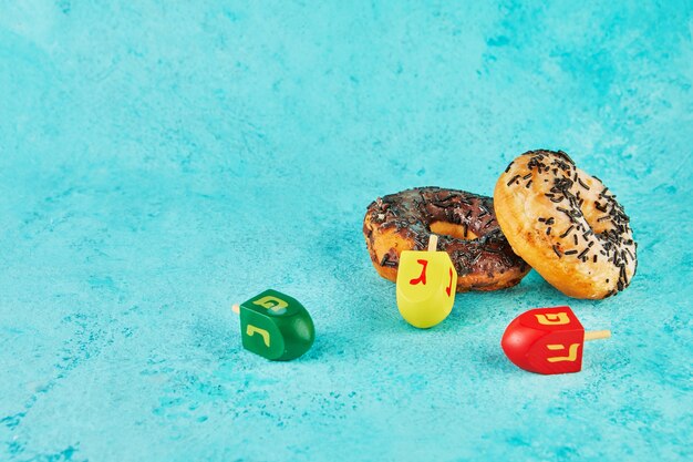 Happy Hanukkah and Hanukkah Sameach - traditional Jewish donuts, spinning tops on blue background