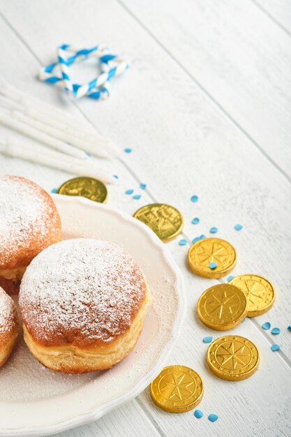 Happy Hanukkah Hanukkah sweet doughnuts gift boxes white candles and chocolate coins on white wooden background Image and concept of jewish holiday Hanukkah Top view