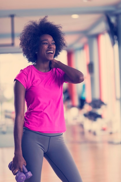 happy healthy african american woman working out in a crossfit gym on weight loss with dumbbells