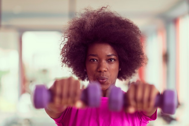 happy healthy african american woman working out in a crossfit gym on weight loss with dumbbells