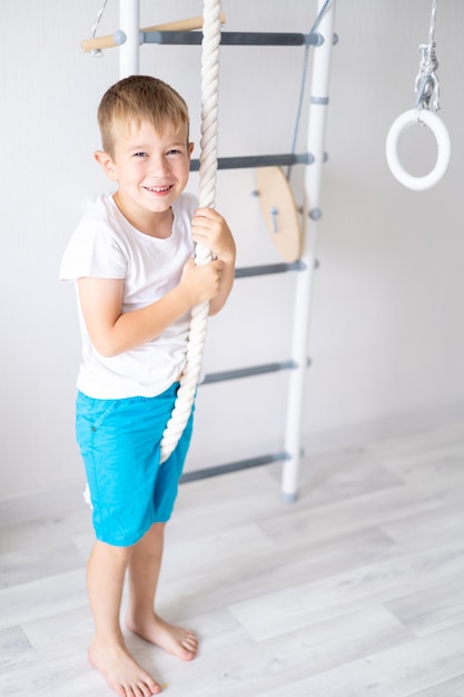 Happy healthy baby boy does sports on the swedish wall of the\
house healthy lifestyle sports at home children\'s sports complex\
ladder