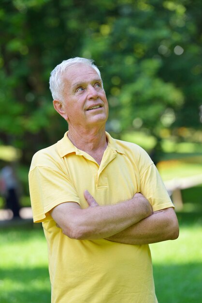 happy healthy and fit elderly man portrait  in green background park