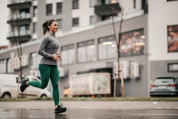 Счастливая здоровая спортсменка бежит по улице в центре города