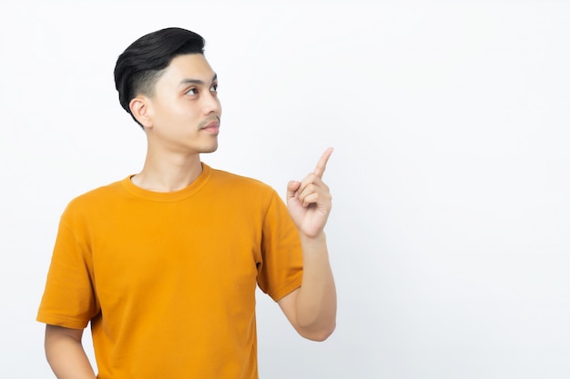 Happy healthy young Asian man smiling with his finger pointing up to copyspace on white.