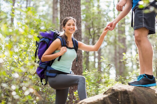 Happy hikers climbing on rock and smiling at camera