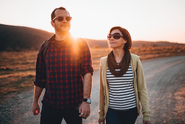 Happy hiking couple on a dirt road during sunset