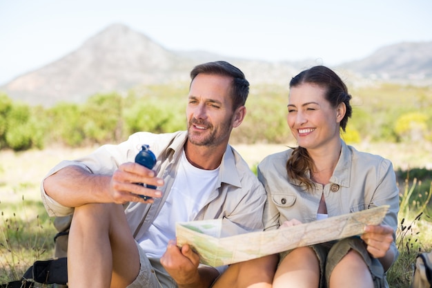 Happy hiking couple reading the map on mountain trail