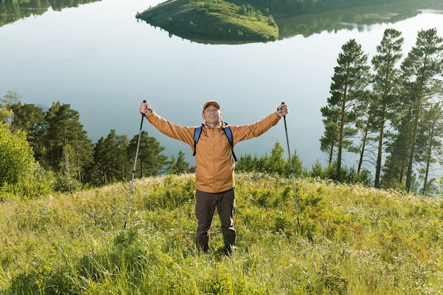 Happy Hiking Success. Backpacker Man Raised Hands Enjoying Nature.