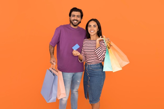 Happy hindu lovers holding shopping bags and bank card