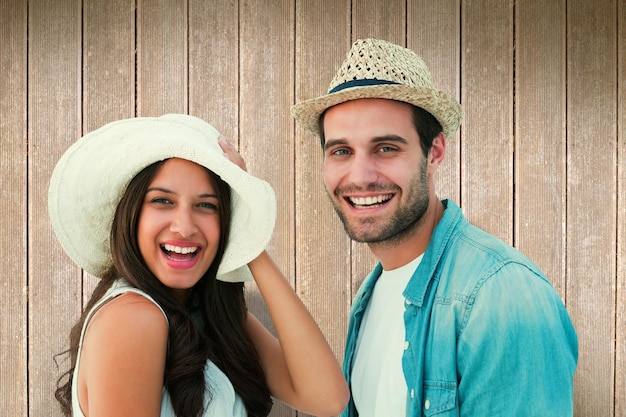 Happy hipster couple smiling at camera against wooden planks