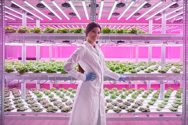 Happy hispanic agronomist standing near hydroponic trays