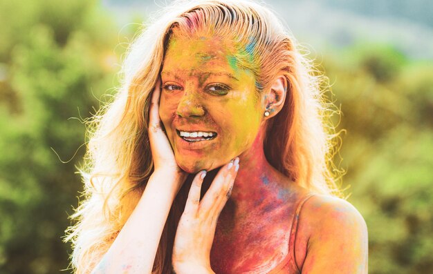 Счастливый фестиваль Холи Смеющаяся молодая женщина с цветным порошком на лице
