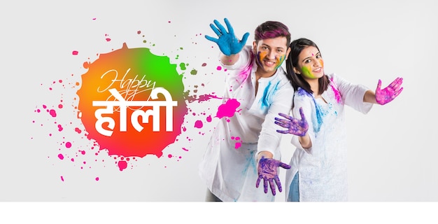 Happy Holi greeting card showing young indian couple playing colours over white background