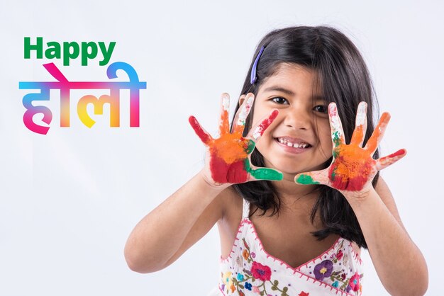 Happy Holi Greeting - Cute little Indian girl with colourful hands, isolated over white background