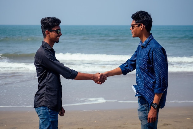 Happy holi two indian stylish mans young friends hugging on the beach by the sea.long-awaited meeting diwali of the brothers in India Goa tropical paradise summer vacation blue sky and ocean