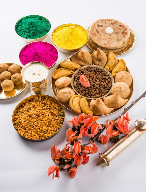 Happy Holi-wenskaart ontworpen met Indiase traditionele zoete en zoute gerechten, bloemen en poederkleuren gerangschikt op witte achtergrond of klei. Selectieve focus