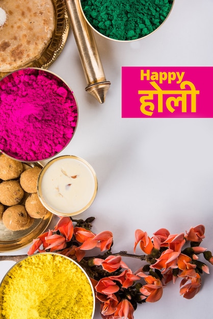 Happy Holi-wenskaart ontworpen met Indiase traditionele zoete en zoute gerechten, bloemen en poederkleuren gerangschikt op witte achtergrond of klei. Selectieve focus