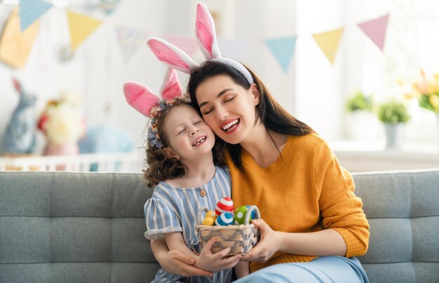 Happy holiday Mother and her daughter with painting eggs Family celebrating Easter