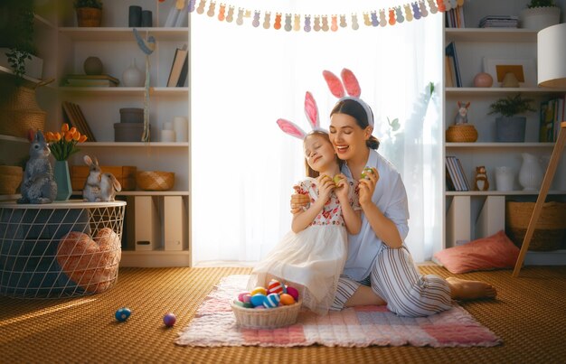 Happy holiday Mother and her daughter with painting eggs Family celebrating