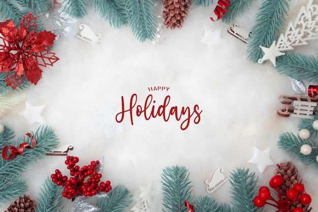 Happy Holidays text with frame made of Christmas decorations flat lay on a snowy background with copy space