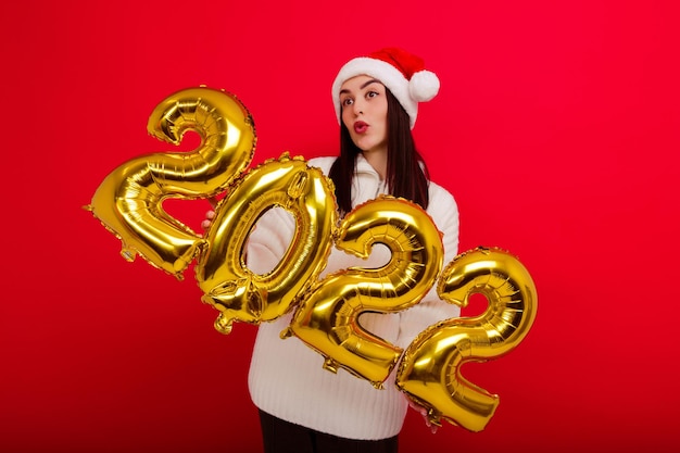 Happy Holidays - a young woman in a red Christmas hat holds the numbers 2022