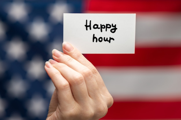 Happy hour text on a card. American flag background.